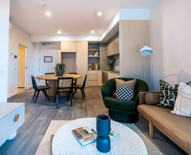 A brightly lit lounge room, dining room and kitchen area with couches, tables and chairs