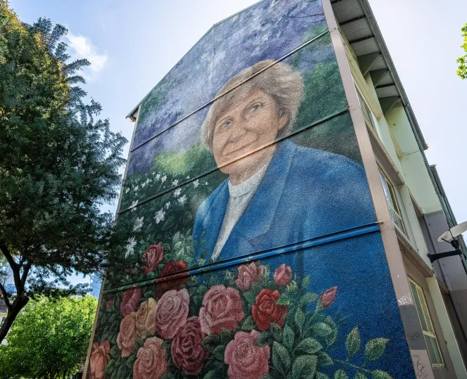 Walk-up building with a mural of a person with flowers