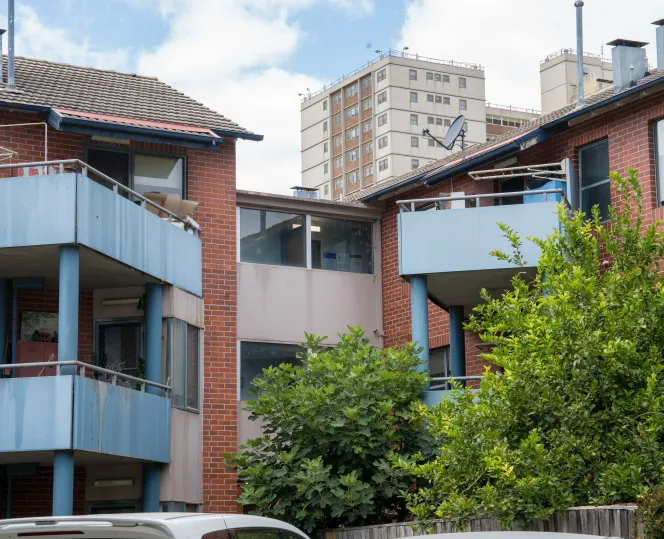 Image of old walk-ups with high apartment buildings in the background