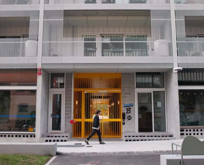 Image of man walking in front of apartment buildings