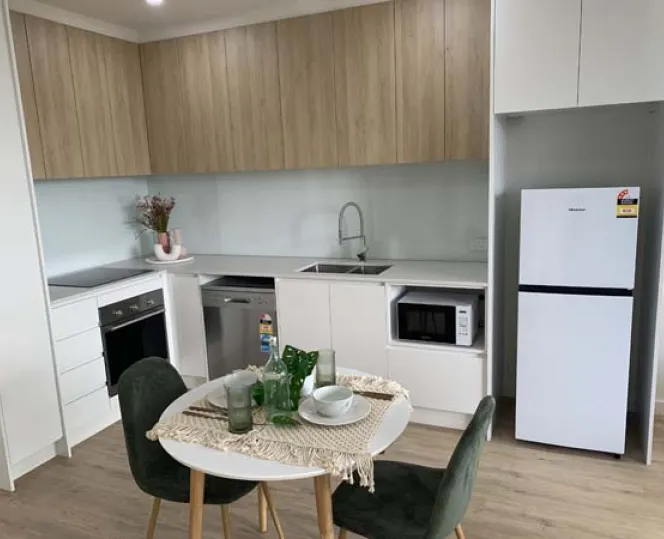 Image of kitchen setting with table fridge sink and cupboards