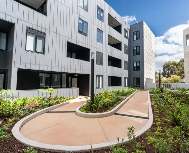 An image of the internal courtyard linking the buildings, featuring a curved walkway bordered by greenery.