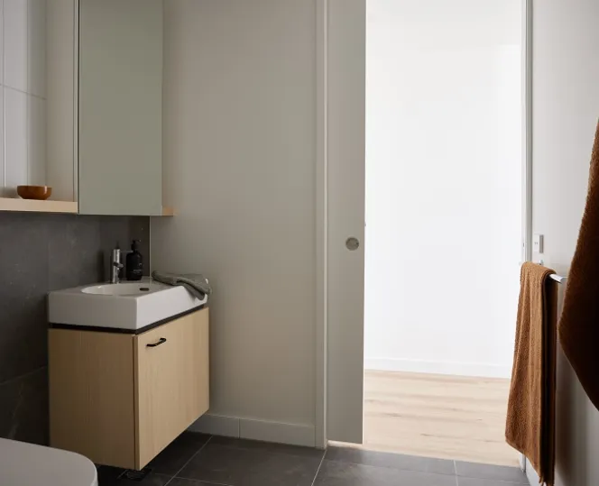 Image of bathroom, with mirror above wash basin along with vanity and white toilet seat