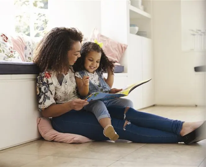 Image of lady sitting down and reading book for the child