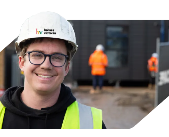 Man smiling while wearing a safety helmet and high-visibility vest  
