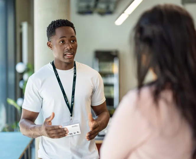 Man with lanyard speaking to woman