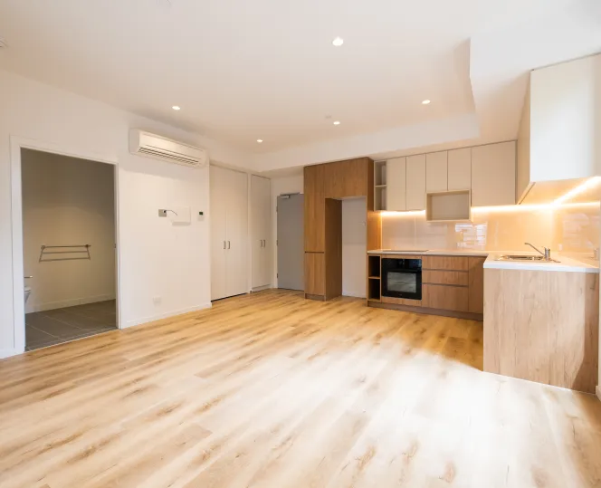 Light-filled living area looking towards the front door, kitchen and bathroom, featuring split-system heating and cooling