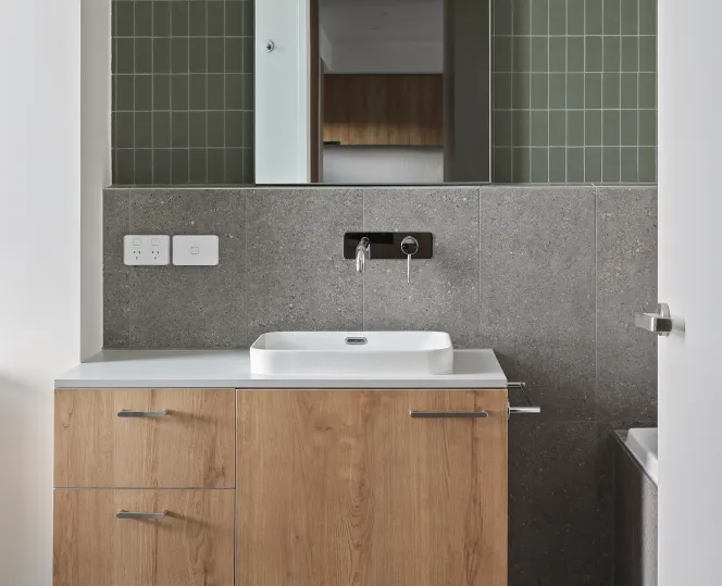 Interior of a modular toilet featuring an installed mirror, vanity, toilet and fixtures.  