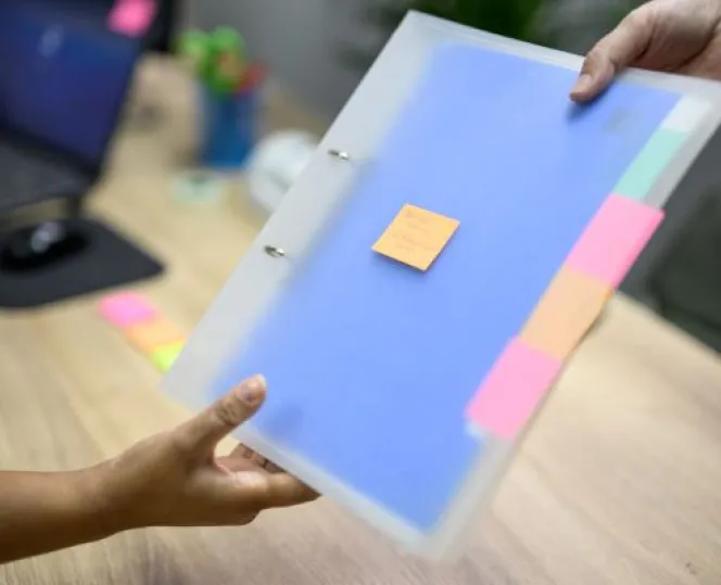 Hospital administrator passing file with sticky notes to nurse