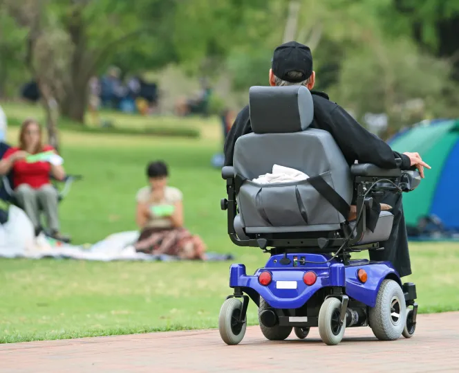 Man in a motorised wheelchair driving through a park