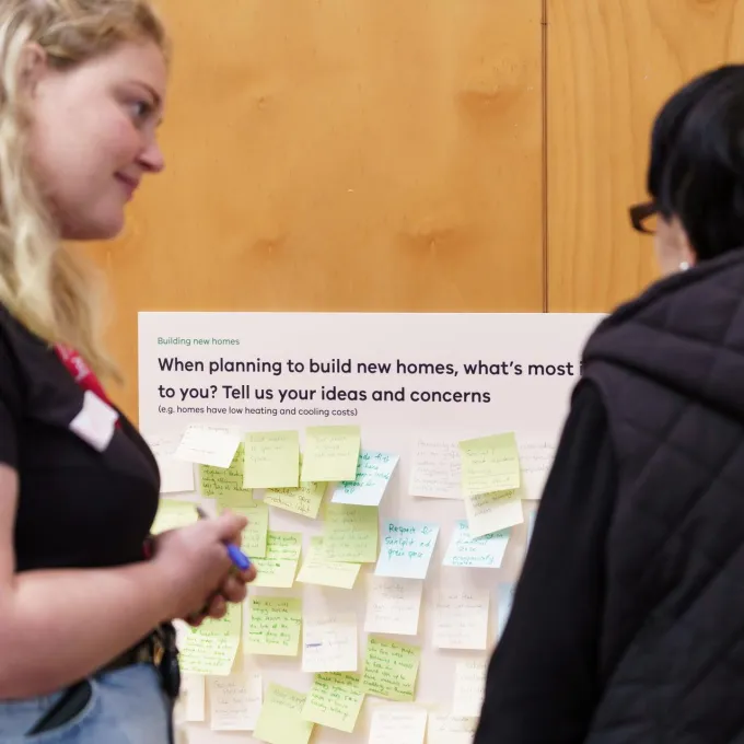 2 people talking in front of a board with sticky notes