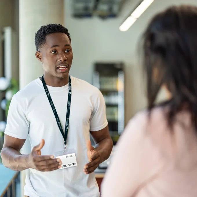 Man with lanyard speaking to woman
