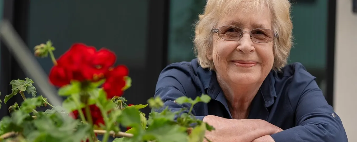 Image of Joy leaning against a fence smiling outdoors