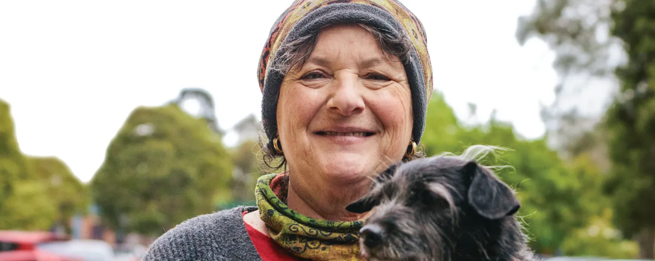 Lady holding a dog and smiling to the camera