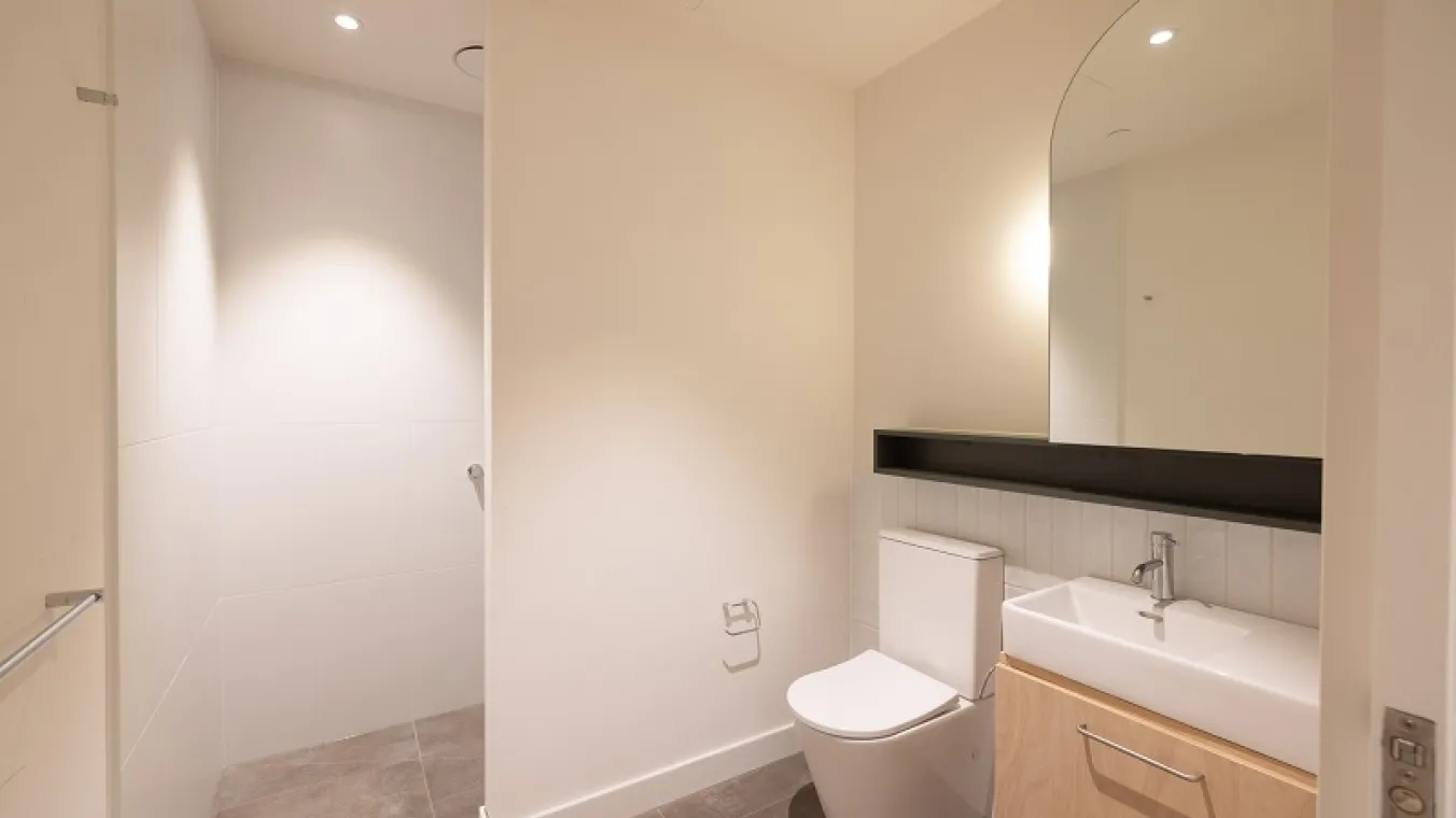 Image of modern bathroom interior featuring a white toilet, washbasin vanity, and a mirror.