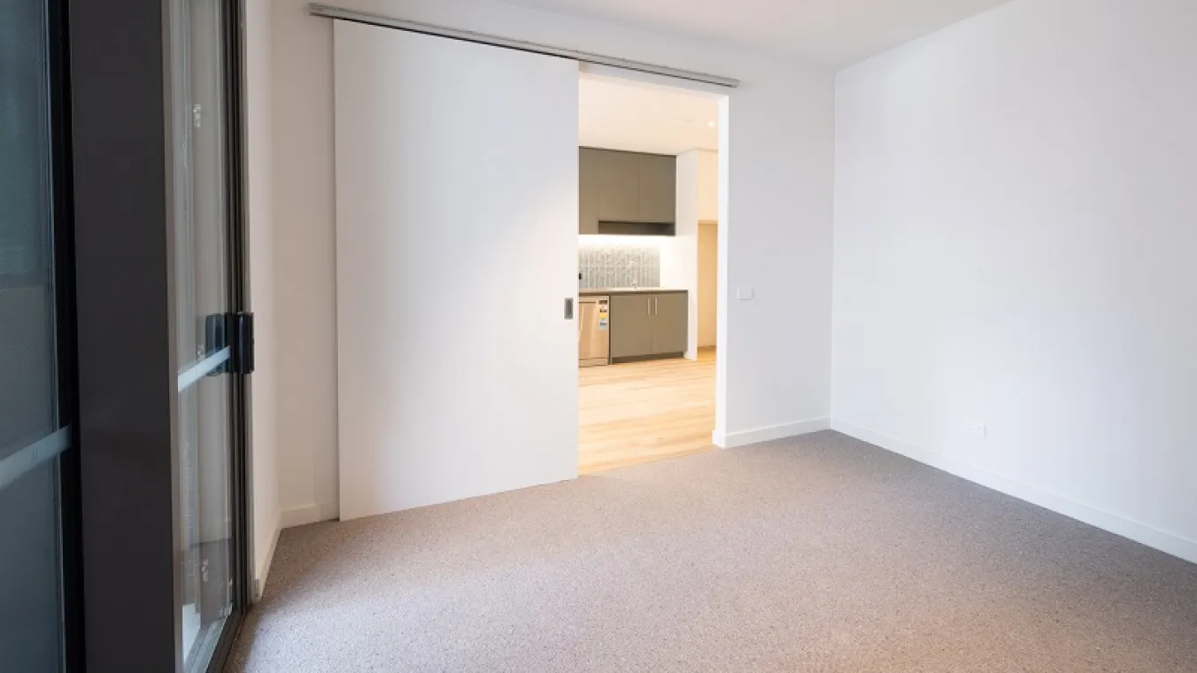 Image of bedroom with carpet and sliding door.
