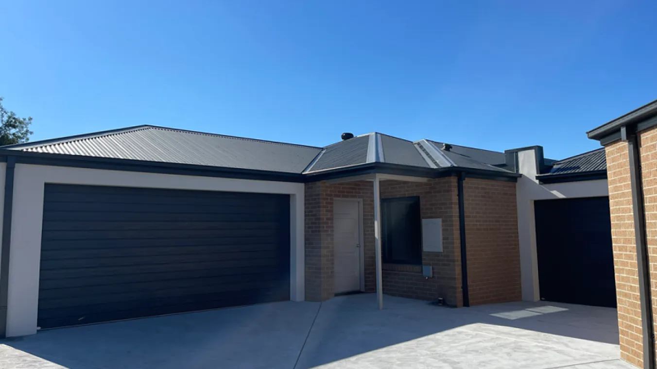 Exterior image of house built with brown bricks and garage for car park 