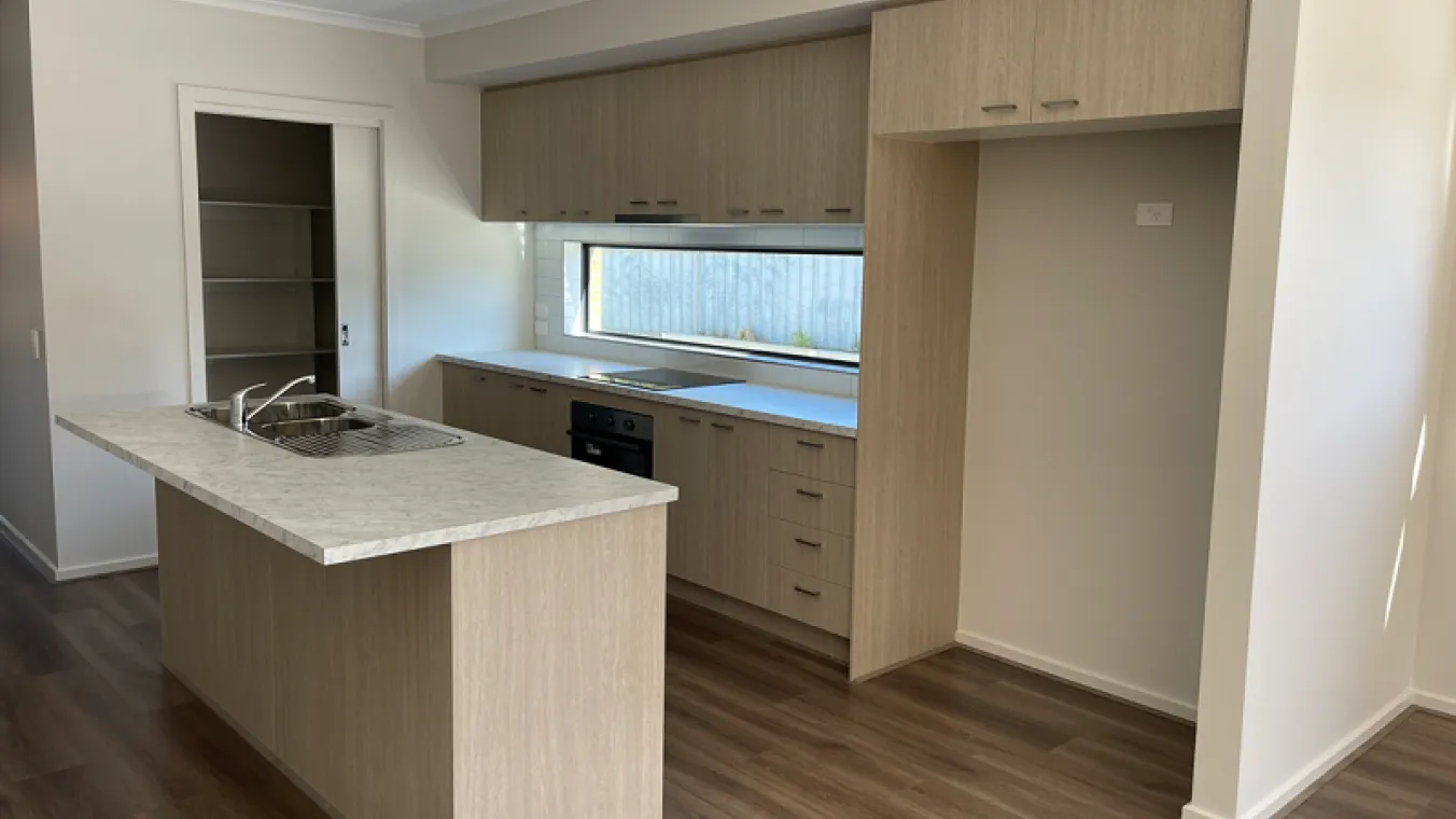 Image of modern kitchen with electric stove, dishwasher,sink,chimney, cabinets, and microwave with cavity for refrigerator