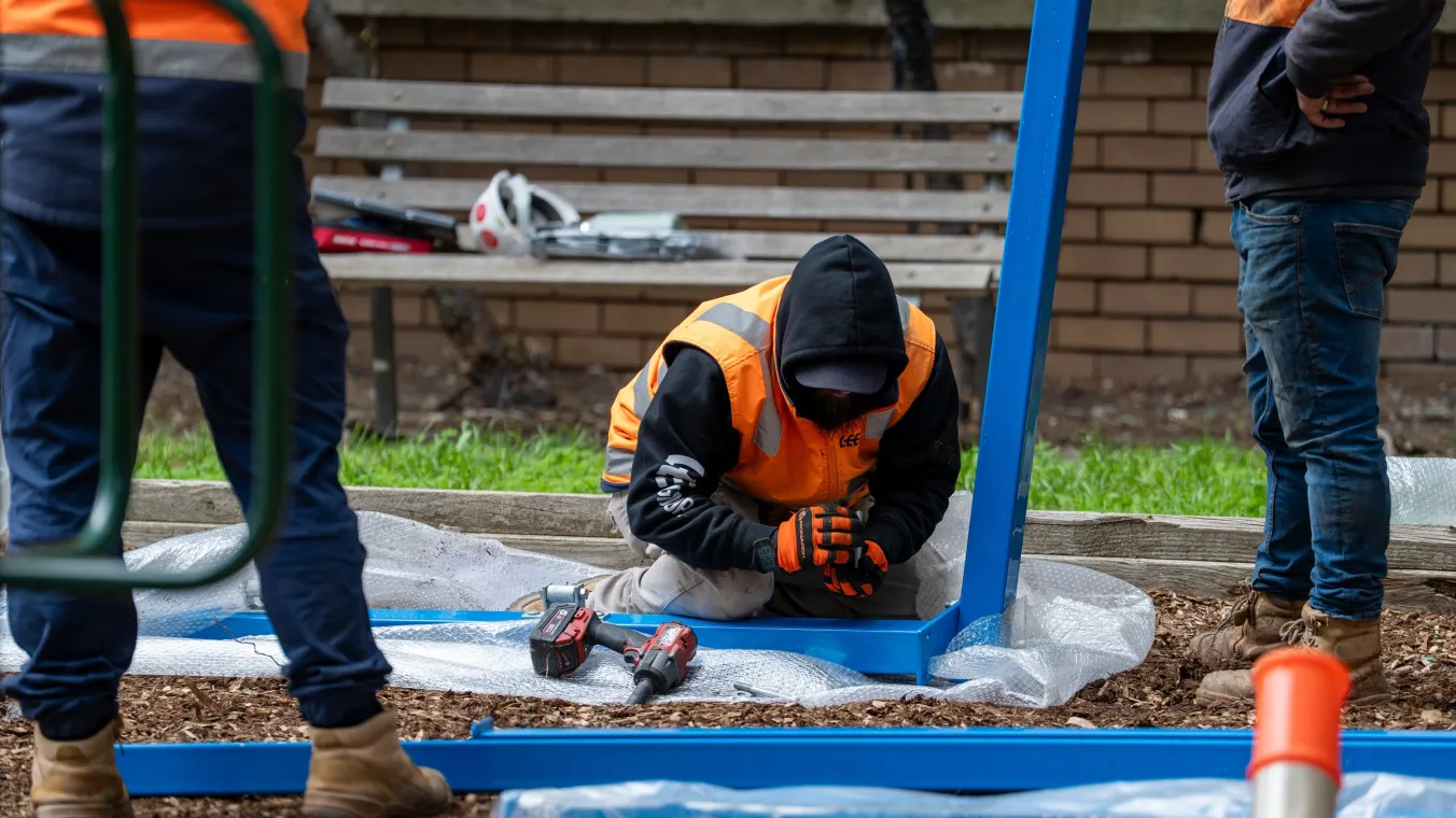 Tradespeople in high-vis installing playground equipment