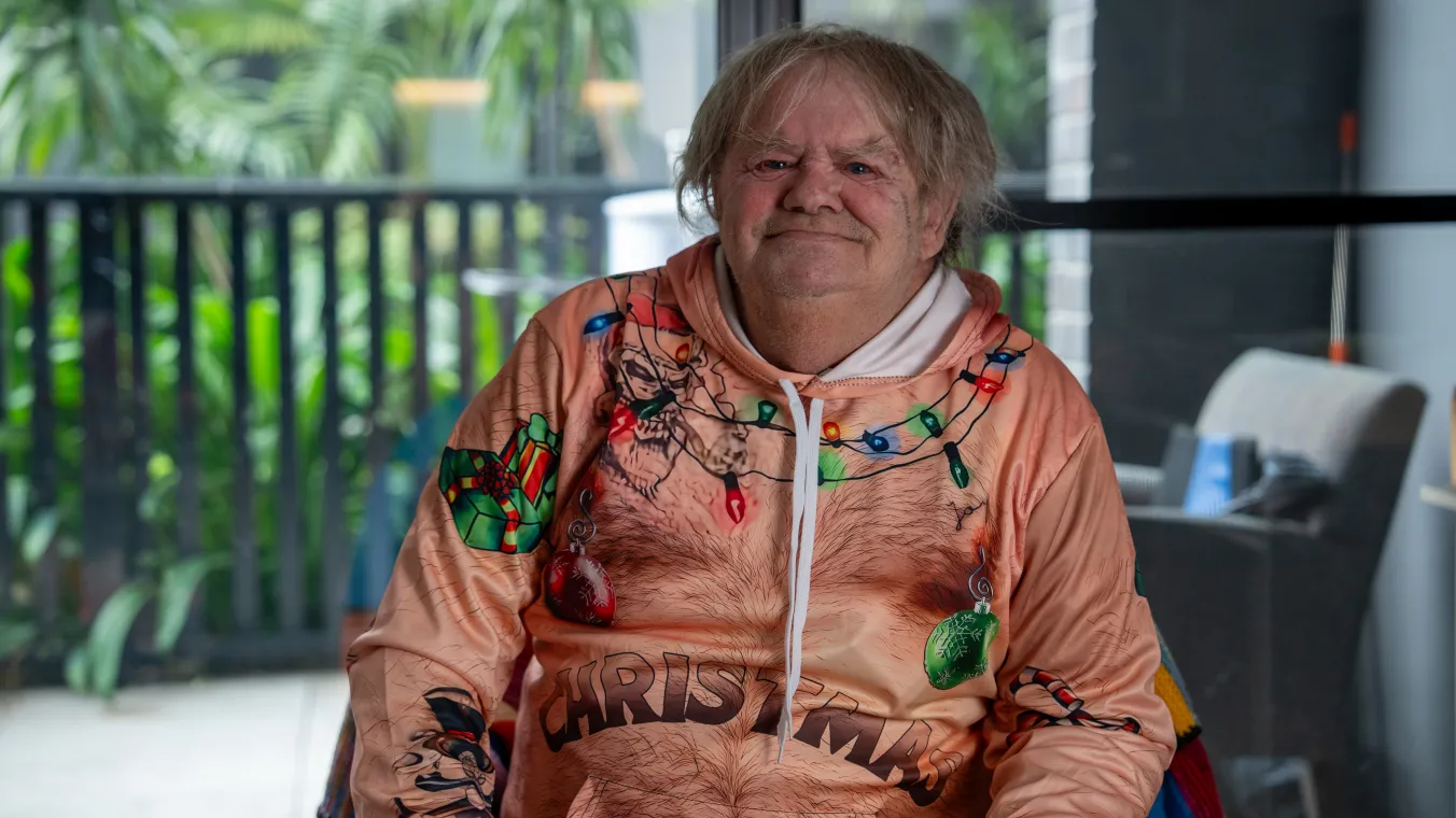 Image of renter sitting on a couch in a festive Christmas jumper, smiling brightly with excitement.