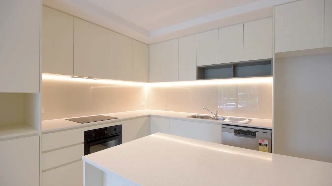 A kitchen with white cabinets, a benchtop, sink, dishwasher, stove and an oven.