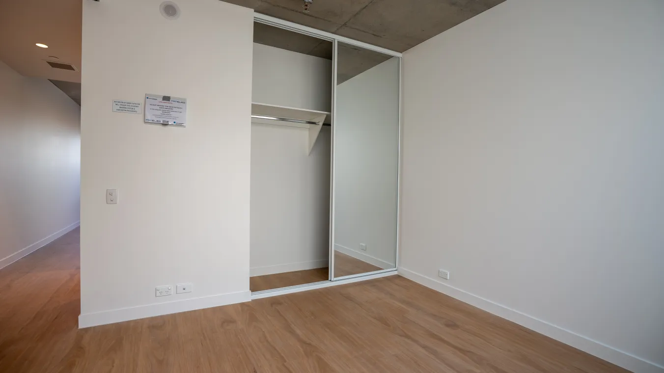Image of bedroom with wooden flooring and a wardrobe featuring sliding mirror doors.  