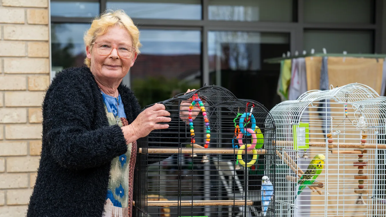 A Summerhill resident standing on her balcony with her colourful parrot.