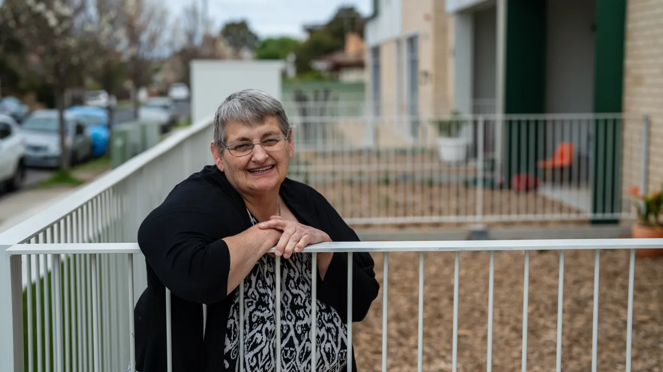 Summerhill resident leaning on a railing, smiling warmly 