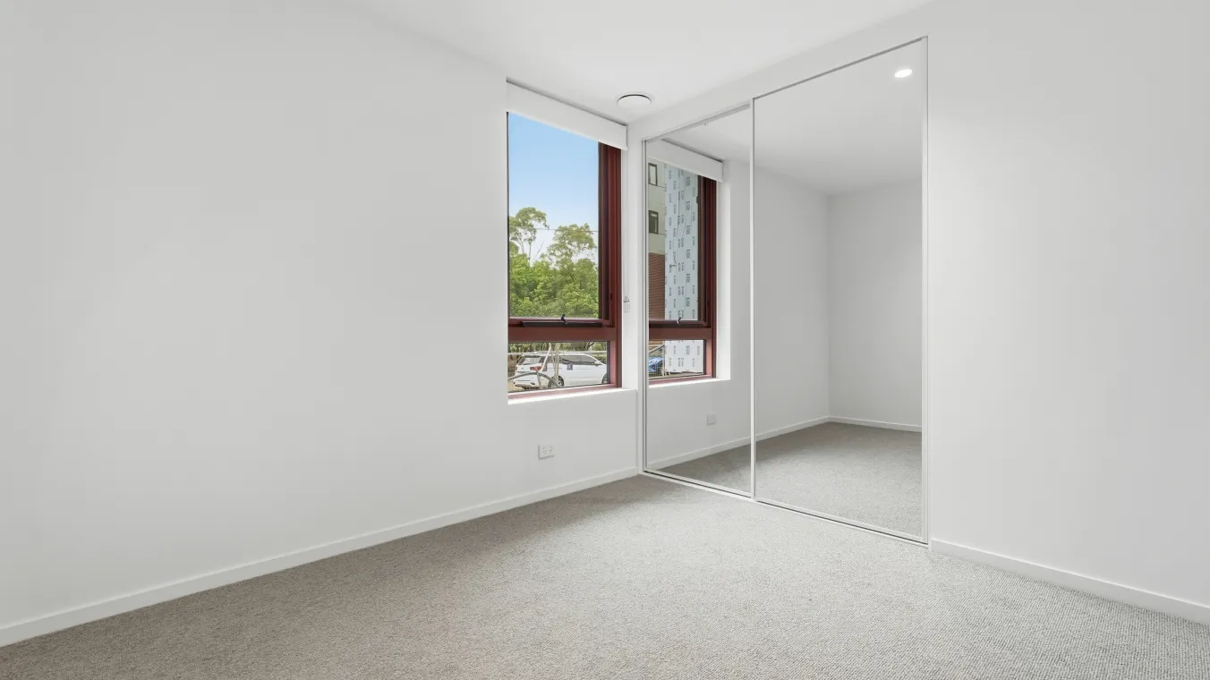 Inside a bedroom with a window and a mirrored wardrobe