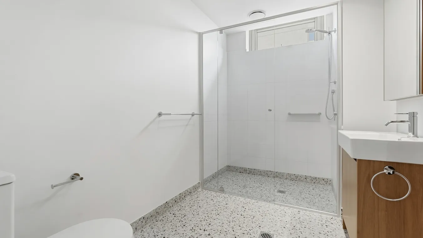 Inside the bathroom with a shower, toilet and a mirrored vanity 