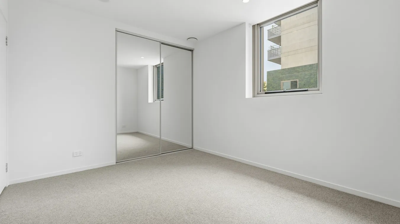 Inside the bedroom with a window and a mirrored wardrobe 