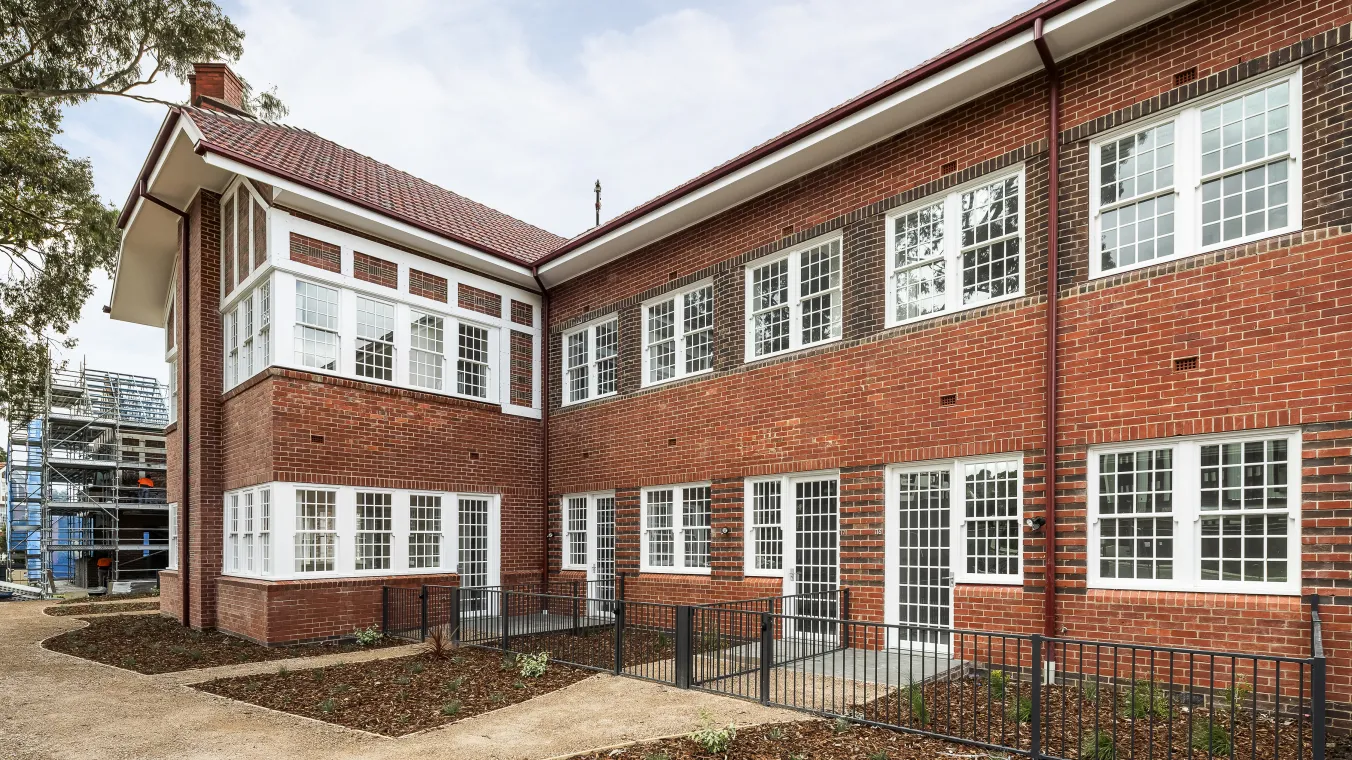 Image of Red-brick building with large glass windows and doors allowing natural sunlight into the interior.  
