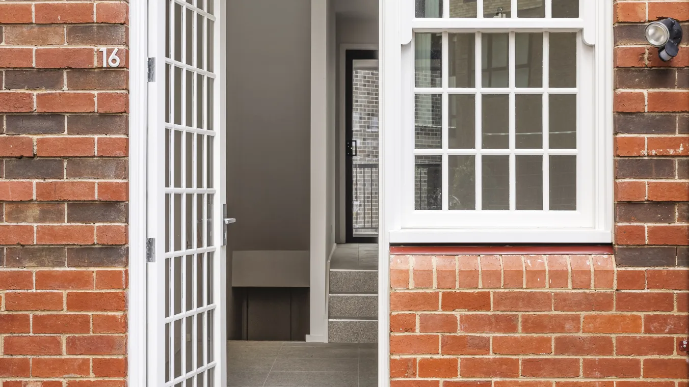 Image of Red-brick building with large glass windows and doors allowing natural sunlight into the interior.  