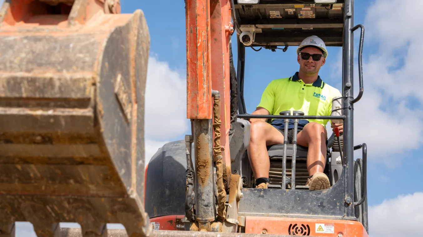 Construction site with a worker operating a bulldozer, moving soil and materials across the site.  