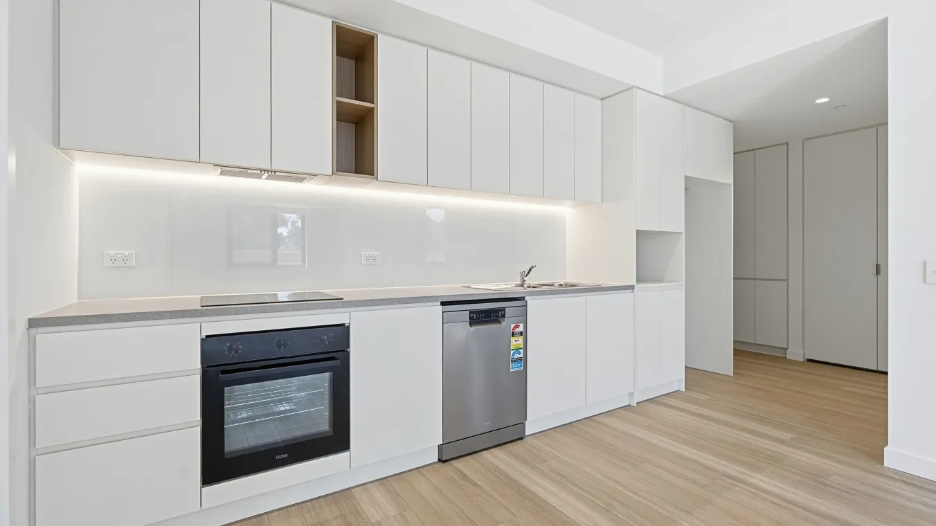 Open-plan living and kitchen area, showing the layout and flow between spaces and the entry to the home.
