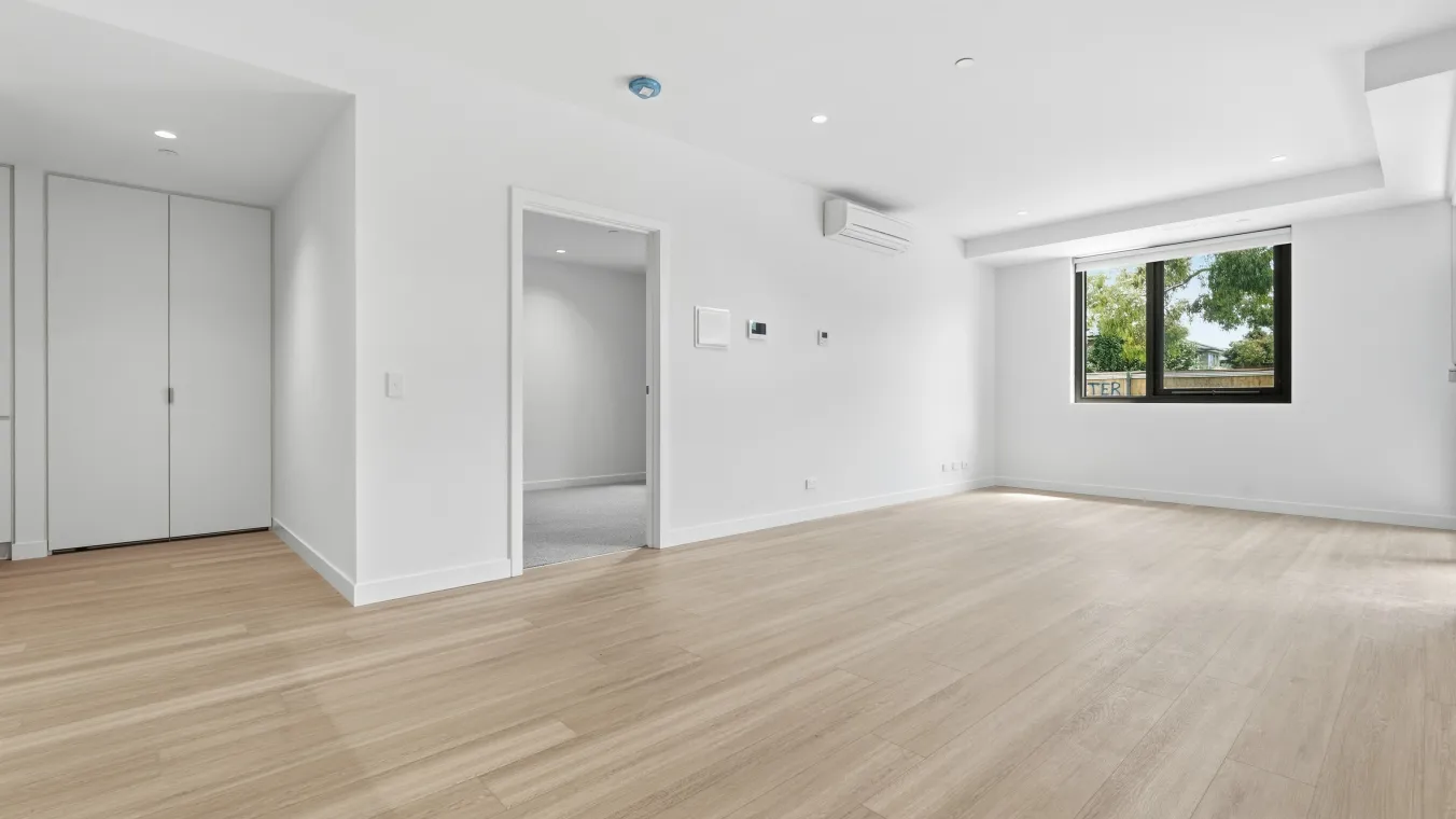 Living area looking towards the bedroom and European laundry, featuring split-system heating and cooling and natural light.
