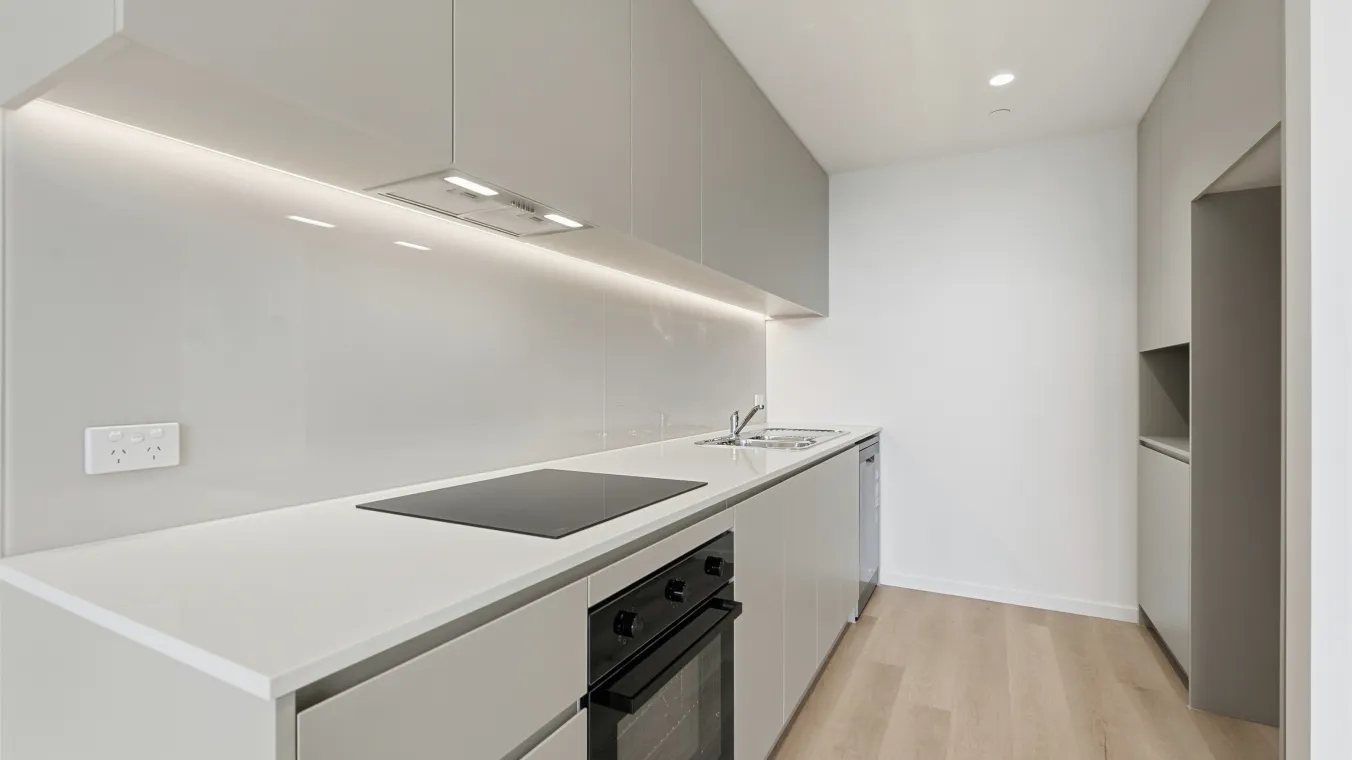 View of the kitchen with white cabinets for storage, stovetop and sink