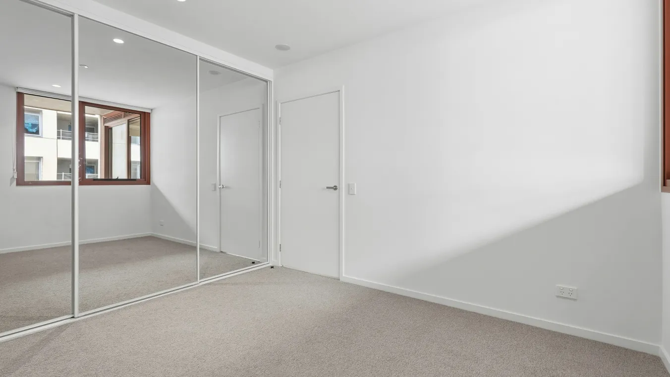 Bedroom filled with natural light, featuring built-in wardrobes with mirrored doors