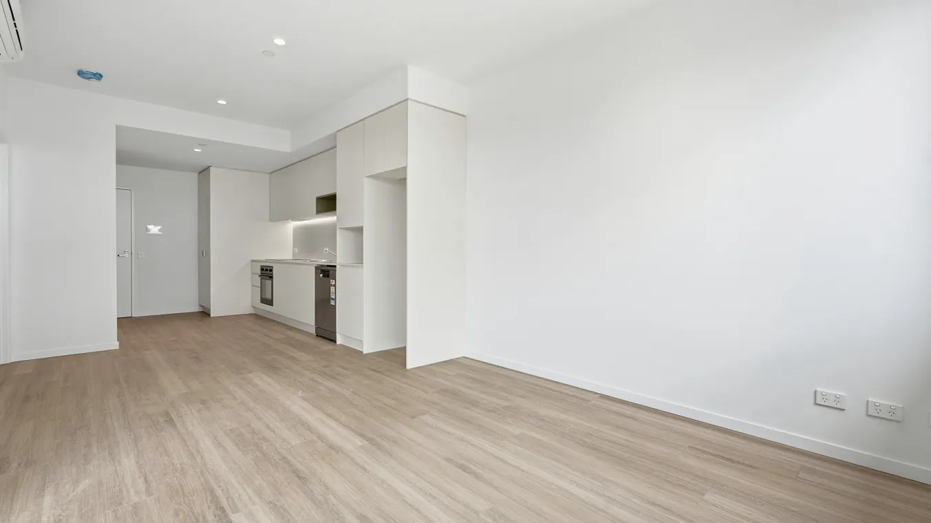 Living area looking towards the front door, kitchen and bathroom, featuring split-system heating and cooling