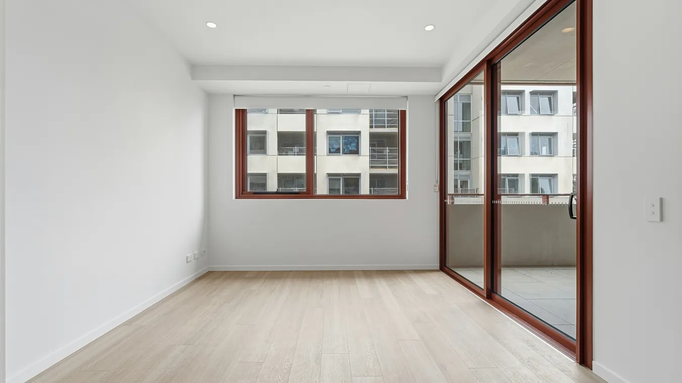 View from the kitchen facing the living area to the private balcony, with large windows and sliding doors filling the space with natural light