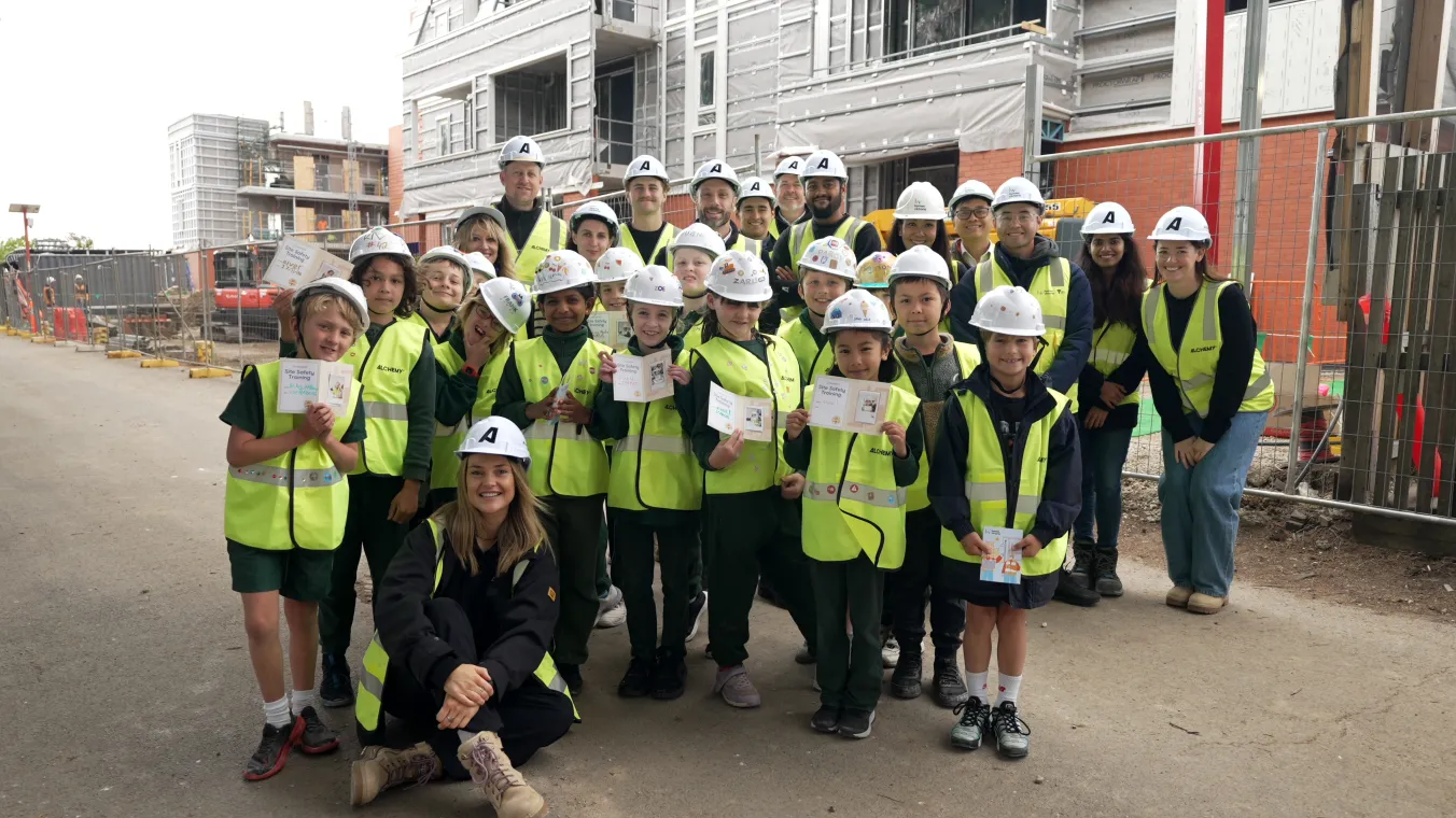 Image of construction site at Ormond road with Homes victoria staff, and the construction staff with kids holding hand made card of site safety training