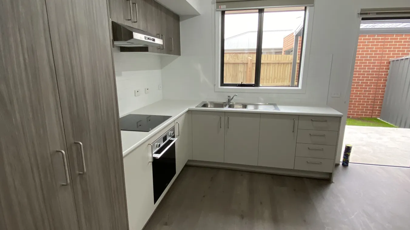  Indoor view of a new home in Werribee featuring wooden flooring, a kitchen area with space for a fridge, built-in oven and electric cooktop.