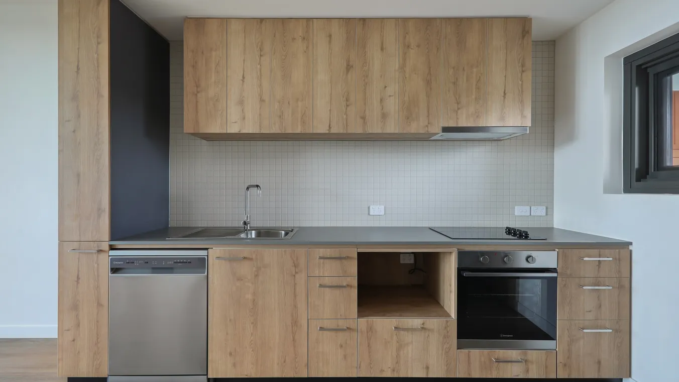 Modern kitchen with white cabinets, built-in oven and dishwasher, and clean counter tops.