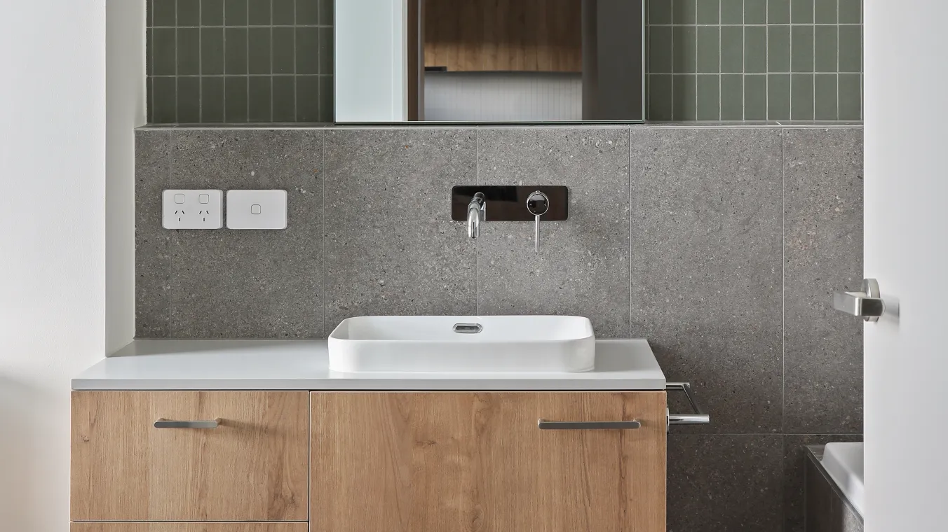 Interior of a modular toilet featuring an installed mirror, vanity, toilet and fixtures.  