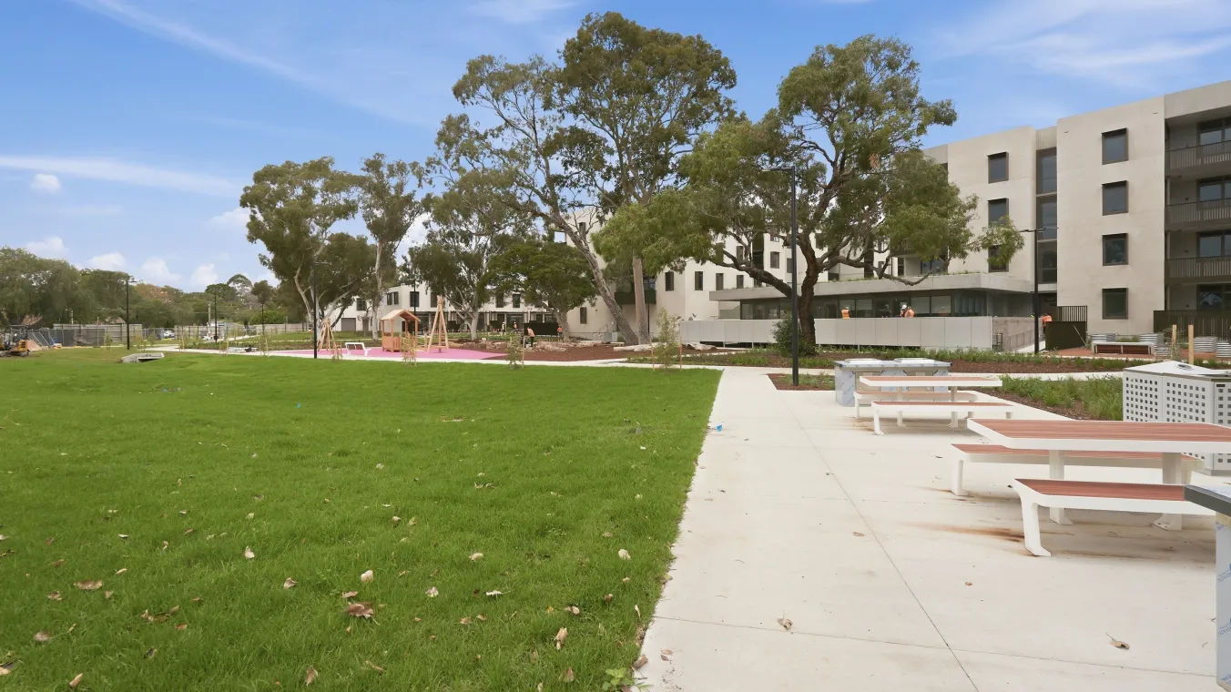 Outdoor shared space with lawns, a picnic table and bench, and a children’s play area.