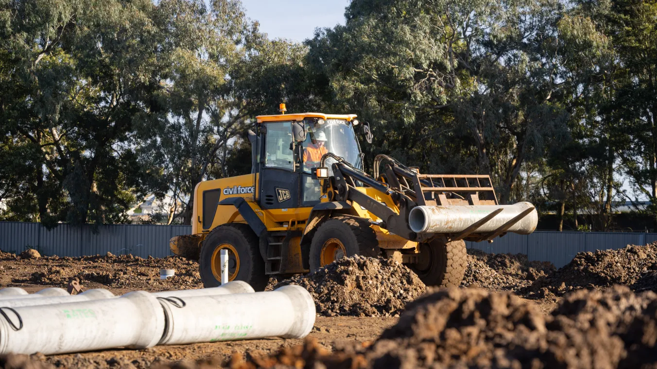 Construction site with a worker operating a bulldozer, moving soil and materials across the site.